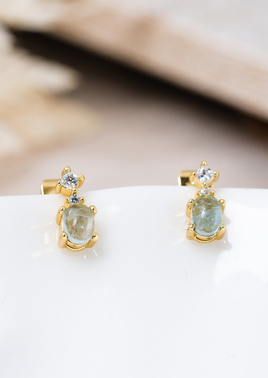 A pair of bigger aquamarine stud earrings in gold with crystal detail.