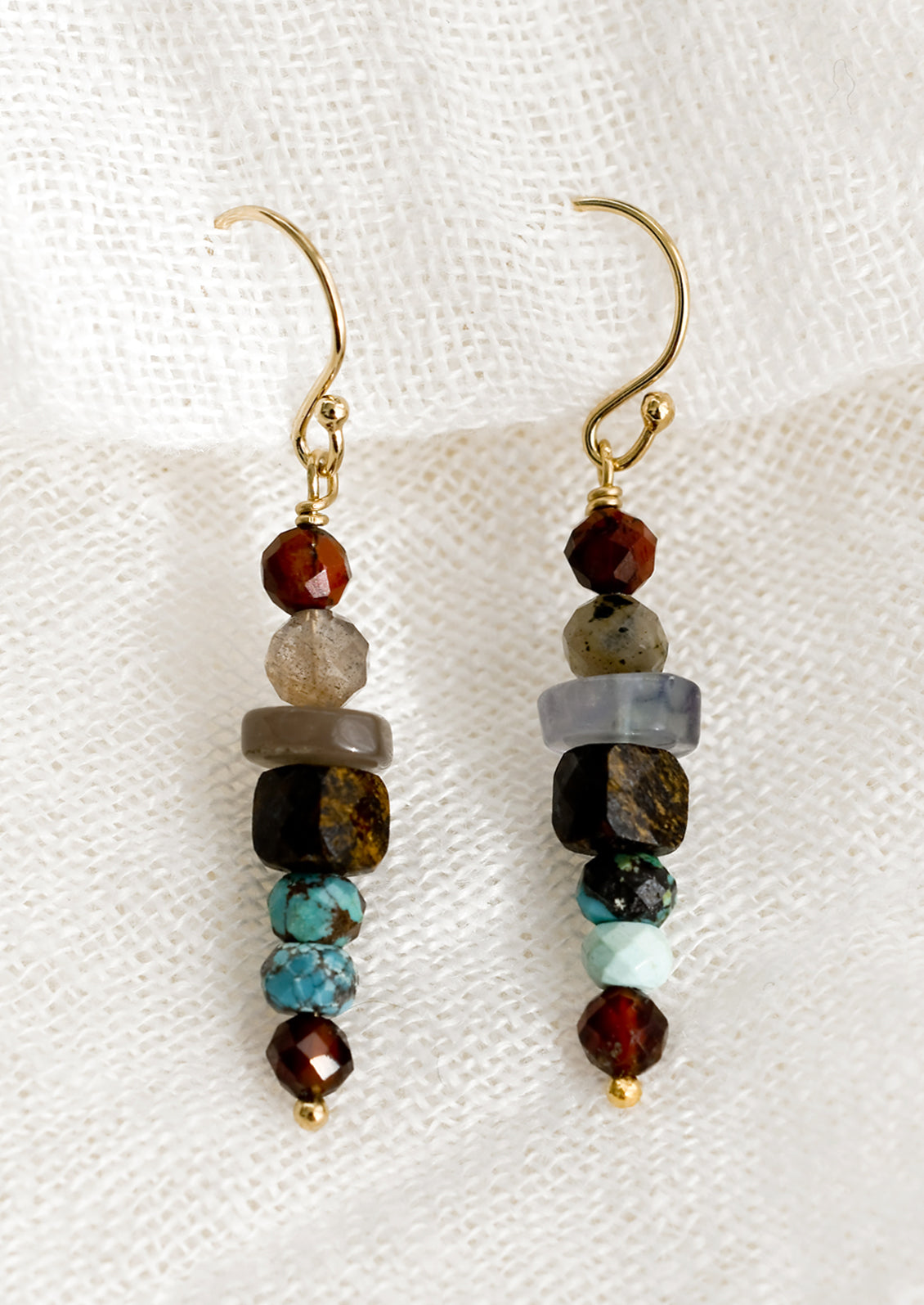 A pair of multicolor beaded mixed garnet gemstone earrings in a straight line.